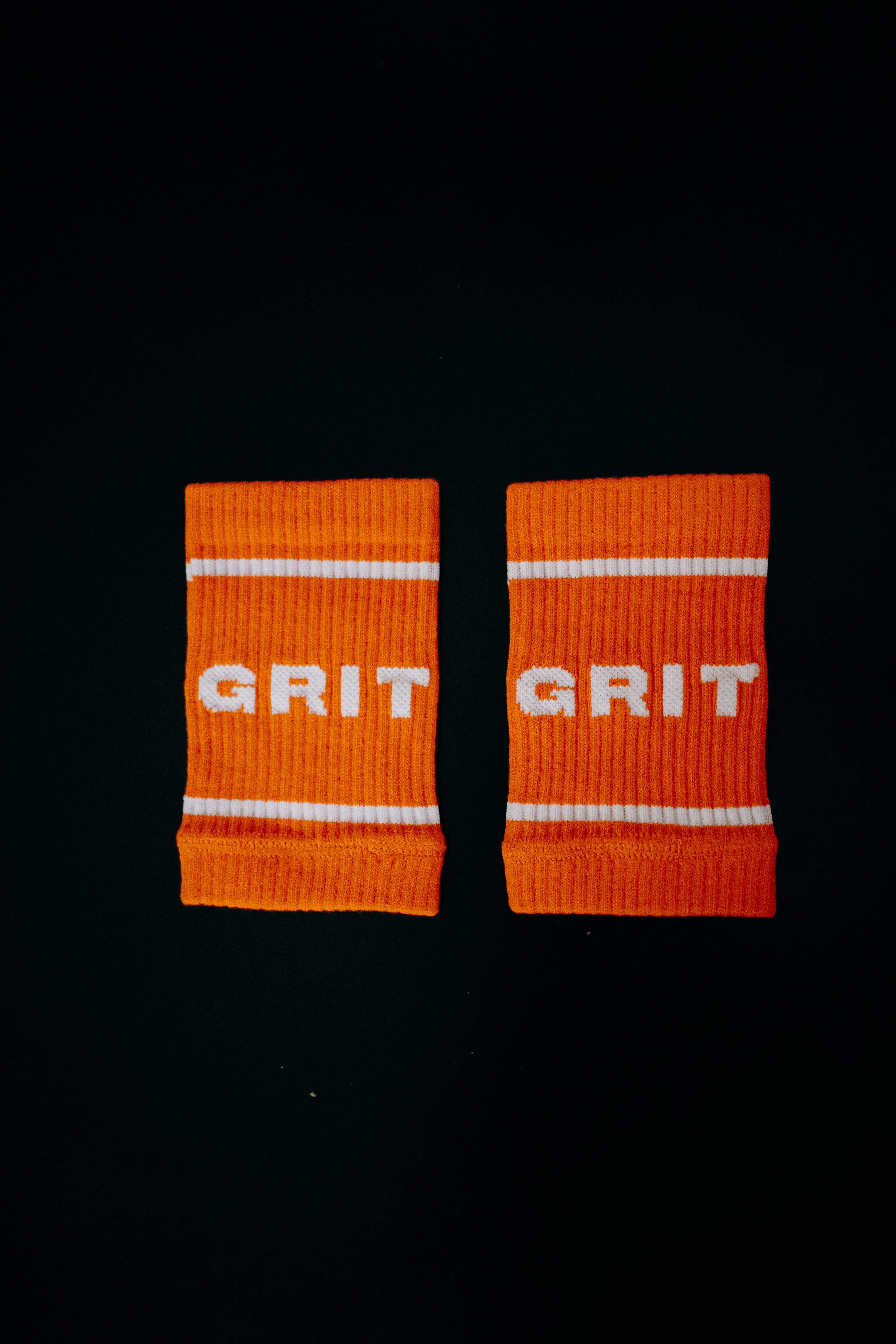 Pair of orange wristbands with 'GRIT' text on a black background