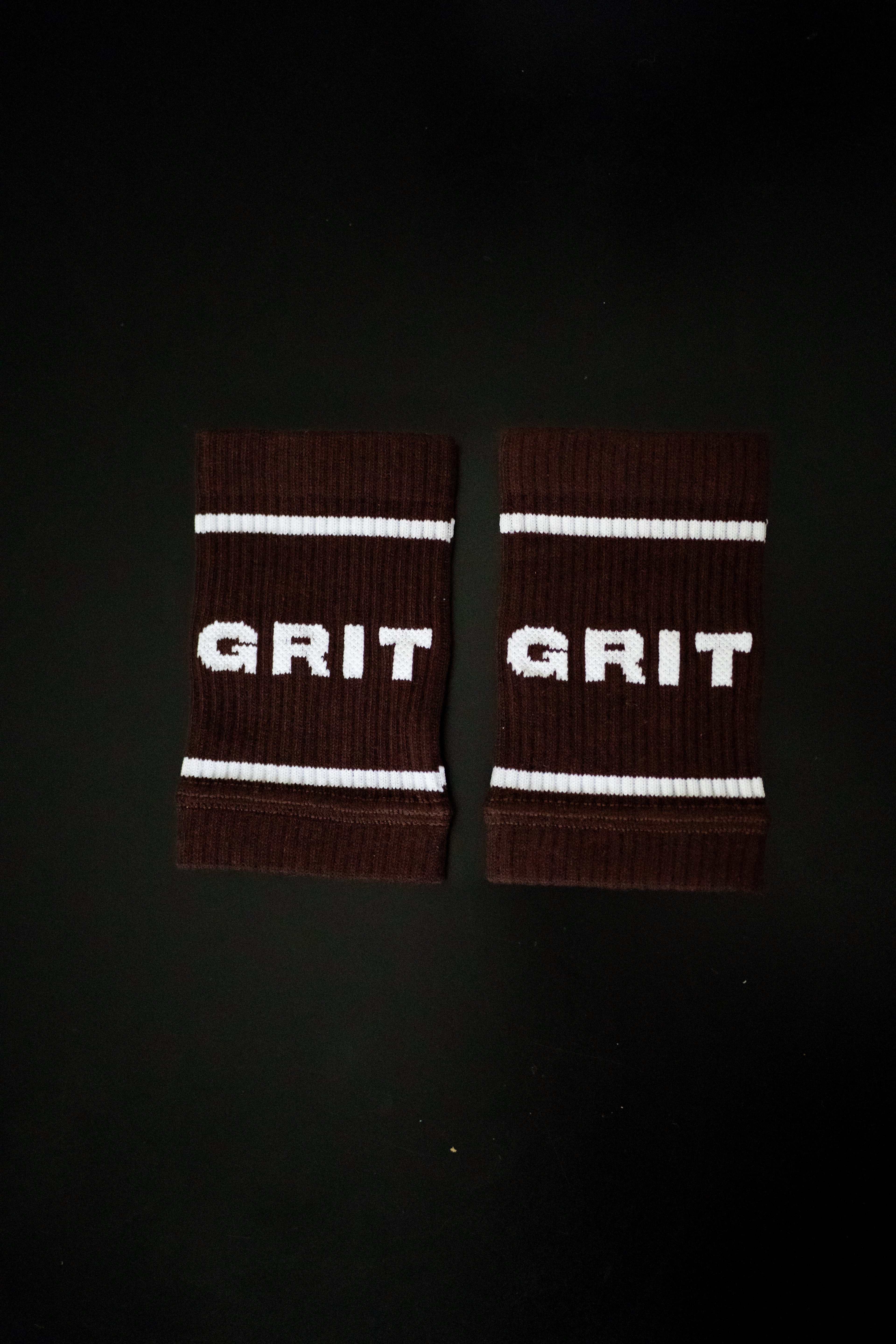 Pair of brown wristbands with 'GRIT' text on a black background